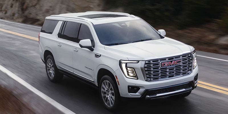 2026 GMC Yukon driving on a scenic highway showcasing its bold exterior design in Dublin, GA